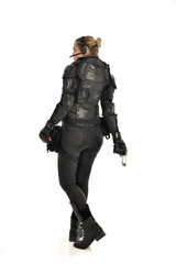 full length portrait of female  soldier wearing black  tactical armour, holding a gun, isolated on white studio background.