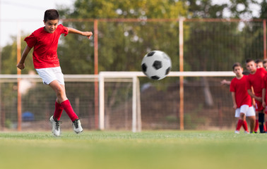 Boy kicking football on the sports field