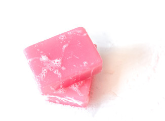 Pink soap on the white background with bubbles.