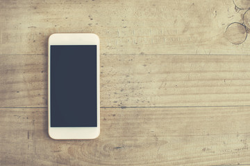White mobile phone on wooden background
