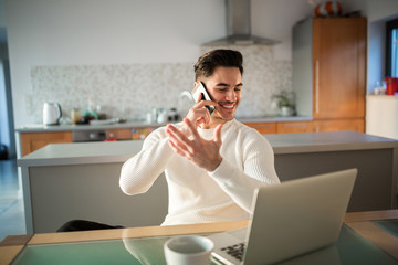 Happy man working at home talking on mobile