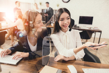 Female operators of the call center together look at the computer screen.