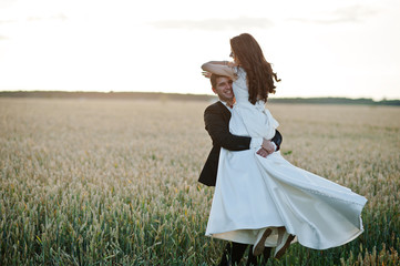Loving wedding couple at field of wheat.