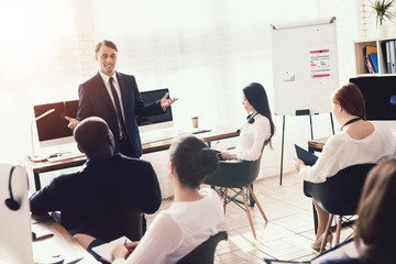 A man of Arabian appearance is giving a lecture for office workers.