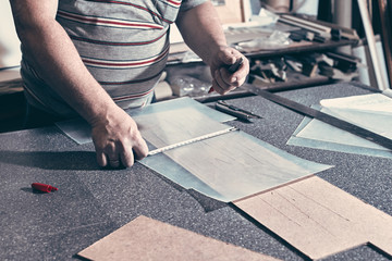 A carpenter uses a framing square for marking a hole in a furniture part.