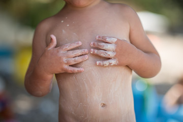 Cute caucasian child applying sunscreen at beach © poplasen