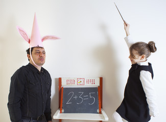 Little girl teaching mathematics to an adult dunce