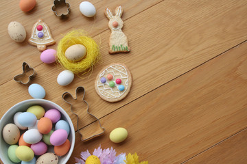 Obraz na płótnie Canvas Easter background. Multicolored choccolate eggs, cookies in shape of bunny, bell and egg,and decoration on wooden table 