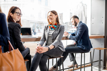 Business people having a conversation during the coffee break sitting near the window in the cafe