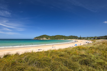Beautiful wide angle view of Matapouri Beach near Whangarei on the North Island of New Zealand. Grass in the foreground. The close by Mermaid rock pools make it a popular tourist destination.