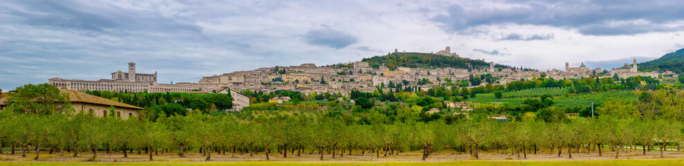 Fototapeta na wymiar Panoramic view of the ancient town of Assisi with dramatic cloudscape and golden harvest fields, Umbria, Italy