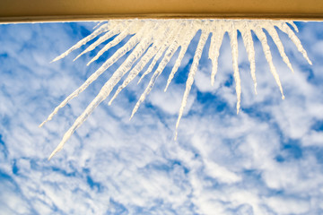 Semicircle of Large Sparkling Icicles on Window Frame at Sky