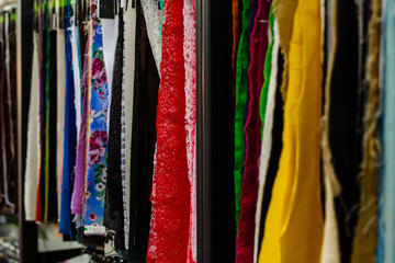 Colorful curtain samples hanging from hangers on rail in a display retail store Multi color fabric texture samples selection of fabrics for interior decoration Curtains,tulle and furniture upholstery
