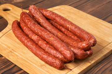 Thin smoked sausage on a wooden background. Close-up.