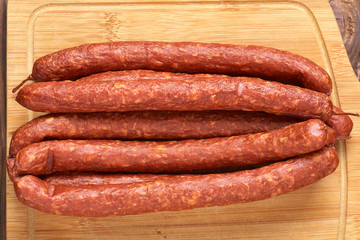 Thin smoked sausage on a wooden background. Close-up.
