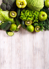 Green vegetables and fruits over wooden background