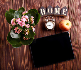 Top view of tablet next to flower, apple, clock and home sign
