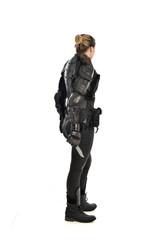 full length portrait of female  soldier wearing black  tactical armour, holding a remote knife, isolated on white studio background.