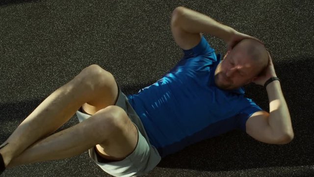 High angle view of man lying on the floor and doing twist crunches at the gym