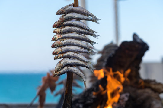 an Holzkohle gegrillte Sardinen mit Flammen und gl&uuml;hender Kohle imHintergrund