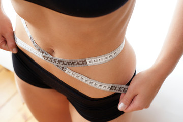 Diät - sportliche Frau misst den Bauchumfang