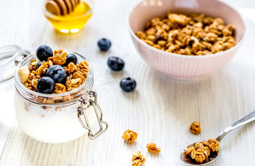 Homemade granola with blueberries in jar on white kitchen backgr