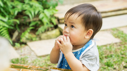 Asian cute child eating a snack in a garden.