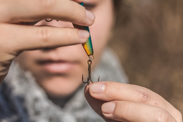 Girl preparing a hook for fishing.