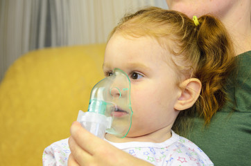Woman with young child doing inhalation with a nebulizer.