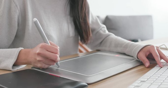 Designer working on drawing pad and computer at home