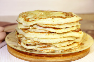 Food. Appetizing baked, thick yeast pancakes are stacked on a plate on the table.