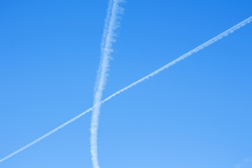 Airplane Lines. A fluffy white "X" against a blue sky background.