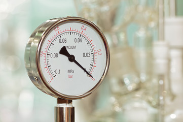 Pressure gauge on a blurry industrial background.
