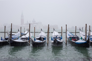 Fototapeta na wymiar Snow on Venetian Gondolas, Grand Channel, St. Mark square, snowing in Venice, Italy, march 2018