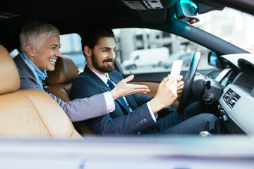 Senior businesswoman sitting in limousine and talking with her driver. Business concept. 