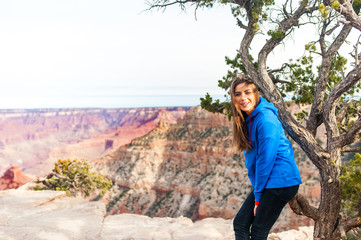 Naklejka premium Travel hiking photo of young beautiful woman at Grand Canyon viewpoint, Arizona, USAm smiling at camera. Healthy active lifestyle.