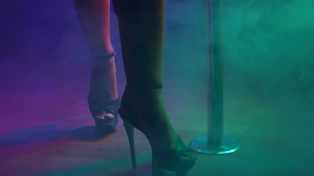 Slender legs of pole dancer in high heels, close-up. Close-up of stripper shoes in the club. Pole dance.