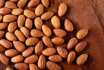 Almonds on textured wooden background, top view.