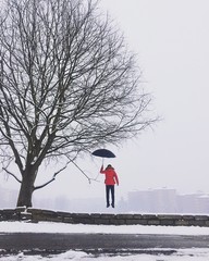 un ragazzo vola sotto la neve con ombrello
