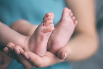 the legs of the baby in the hands of the mother