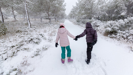 Fototapeta na wymiar couple d'enfants marchant dans la neige fraîche