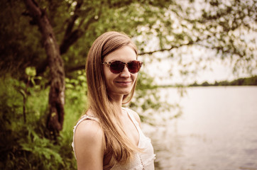 Attractive blond woman in sunglasses against nature background