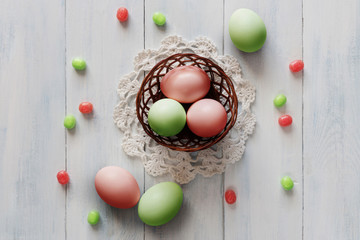 Fototapeta na wymiar Colored easter eggs with candies in small basket