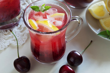 Homemade lemonade with cherries in glasses on white table