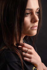 Portrait of a beautiful young girl with long dark hair, evening make-up on a black background.