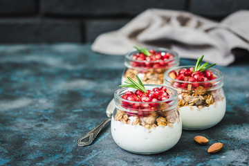 Pomegranate vanilla yogurt granola parfait on dark blue background. Selective focus, space for text. 