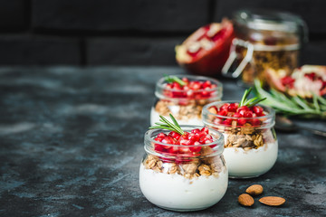 Honey ginger pomegranate greek yogurt granola parfait on dark blue background. Selective focus, space for text. 