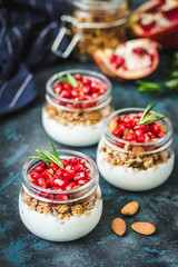 Pomegranate coconut yogurt granola parfait on dark blue background. Top view, copy space.