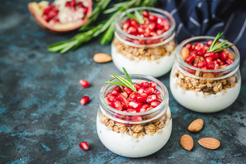 Pomegranate greek yogurt granola breakfast parfait on dark blue background. Selective focus, space for text. 