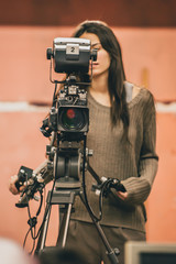 Naklejka premium Behind the scene. Female cameraman shooting film scene with camera